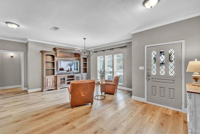 Foyer entrance with crown molding, light wood finished floors, a textured ceiling, baseboards, and visible vents | Image 5