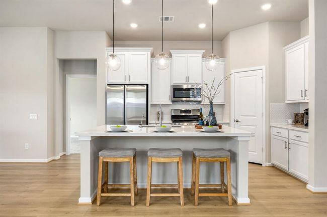 Beautiful kitchen with a 3-seater island, LVP flooring, stainless steel appliances and gas range. | Image 6