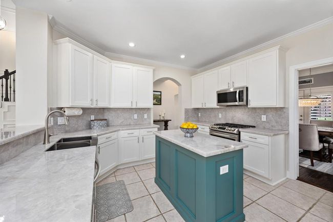 Stunning kitchen includes white cabinetry, illuminato quartzite counters and backsplash, and SS appliances. | Image 13