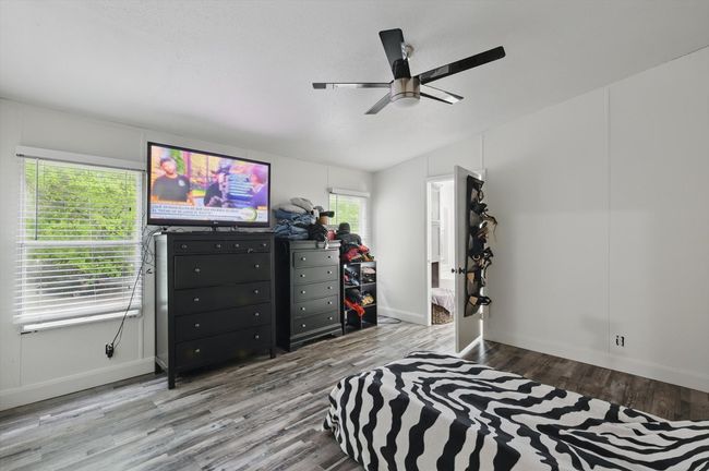 Bedroom with ceiling fan, lofted ceiling, wood finished floors, and baseboards | Image 12