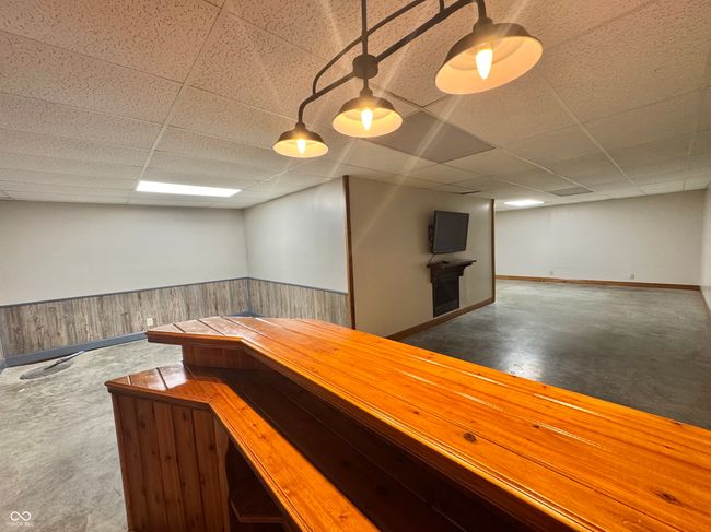indoor dry bar featuring wainscoting, a paneled ceiling, baseboards, and finished concrete floors | Image 64
