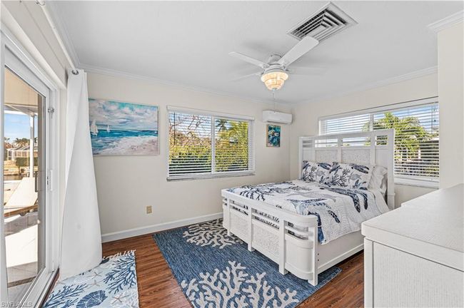 Bedroom with dark wood finished floors, visible vents, access to exterior, a wall unit AC, and ornamental molding | Image 18