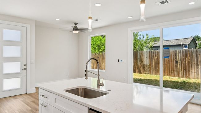 Kitchen with light wood-style flooring, light stone counters, white cabinets, recessed lighting, and decorative light fixtures | Image 11