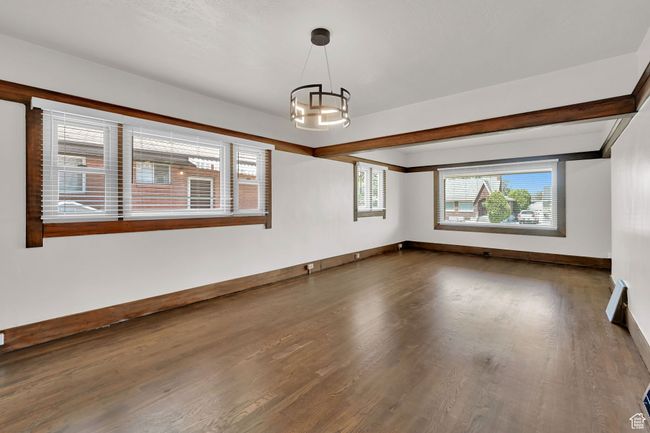 Unfurnished room featuring wood finished floors, a chandelier, and baseboards | Image 7
