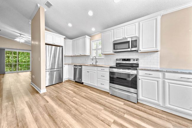 Kitchen featuring visible vents, lofted ceiling, a healthy amount of sunlight, a textured ceiling, and stainless steel appliances | Image 21