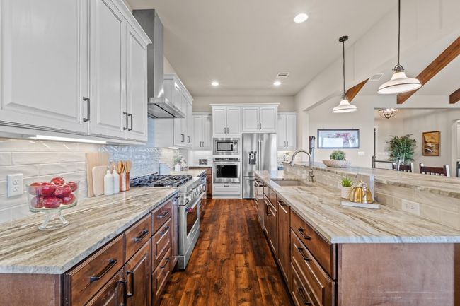 Kitchen with dark wood finished floors, a sink, wall chimney exhaust hood, high quality appliances, and white cabinetry | Image 12