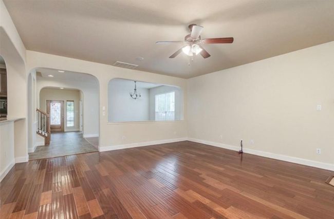 Living room featuring arched walkways, a chandelier, wood finished floors, and a ceiling fan | Image 12