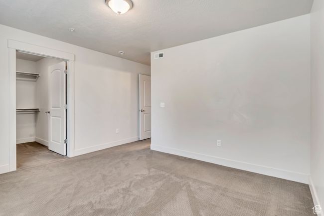 Unfurnished bedroom with carpet flooring, a walk in closet, and a closet | Image 4