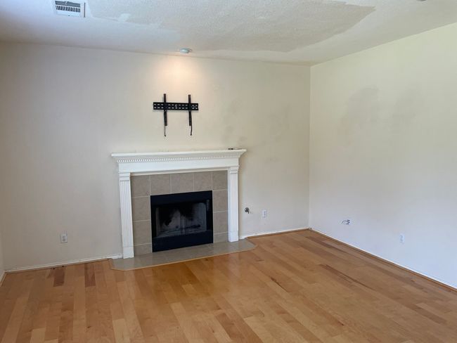 Unfurnished living room featuring wood finished floors and a tiled fireplace | Image 5