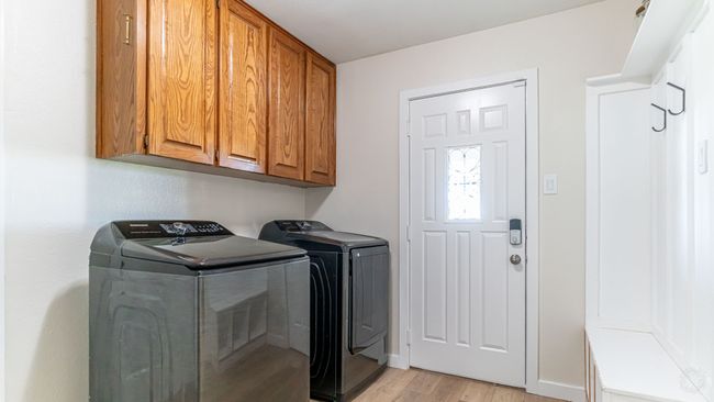 Laundry room with cabinet space, washer and clothes dryer, light wood finished floors, and baseboards | Image 24