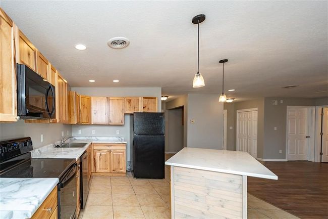 Kitchen featuring visible vents, black appliances, a sink, a center island, and recessed lighting | Image 20