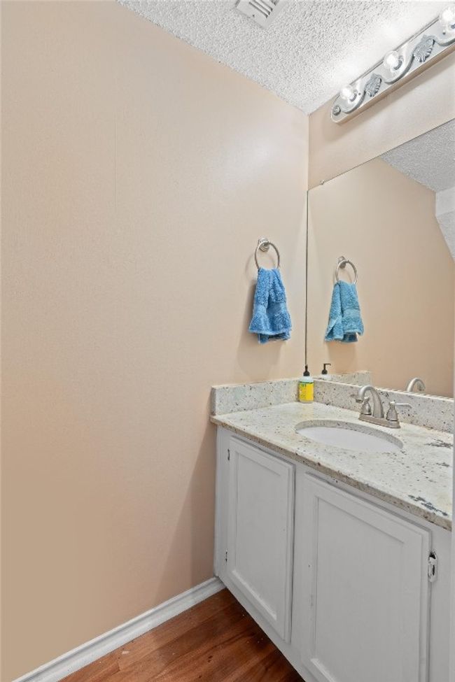 Bathroom with a textured ceiling, vanity, and wood finished floors | Image 11