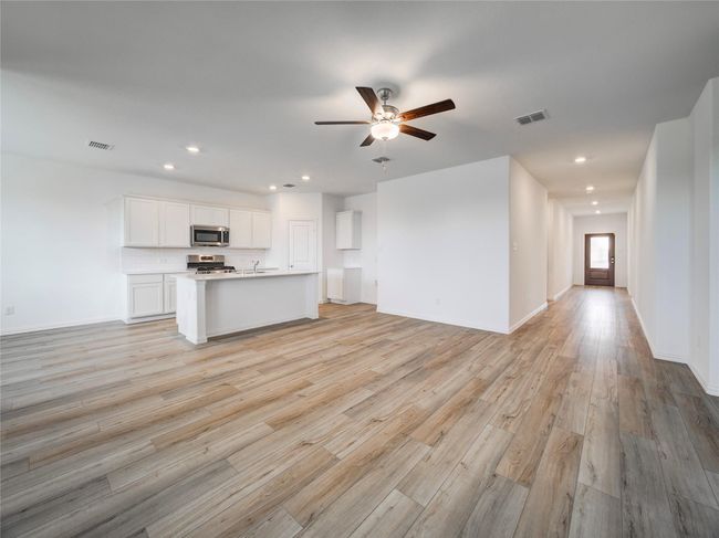 Kitchen with stainless steel appliances, open floor plan, a ceiling fan, white cabinetry, and light wood-style floors | Image 10