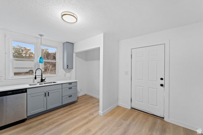 Kitchen featuring light countertops, a sink, light wood-type flooring, gray cabinets, and stainless steel dishwasher | Image 10
