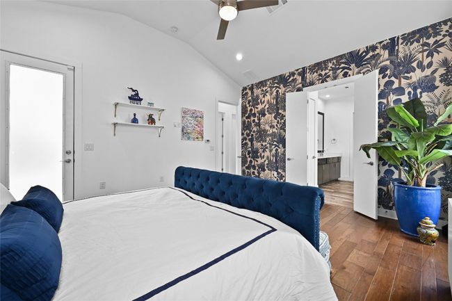 Bedroom featuring vaulted ceiling, wood-type flooring, wallpapered walls, ceiling fan, and ensuite bath | Image 13