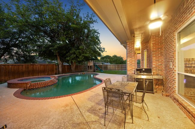 View of pool with a patio, a fenced backyard, and a pool with connected hot tub | Image 34
