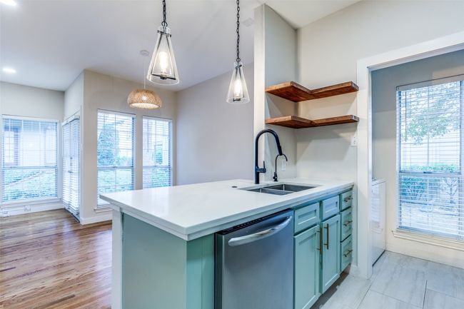 Kitchen featuring stainless steel dishwasher, open shelves, healthy amount of natural light, and hanging light fixtures | Image 7