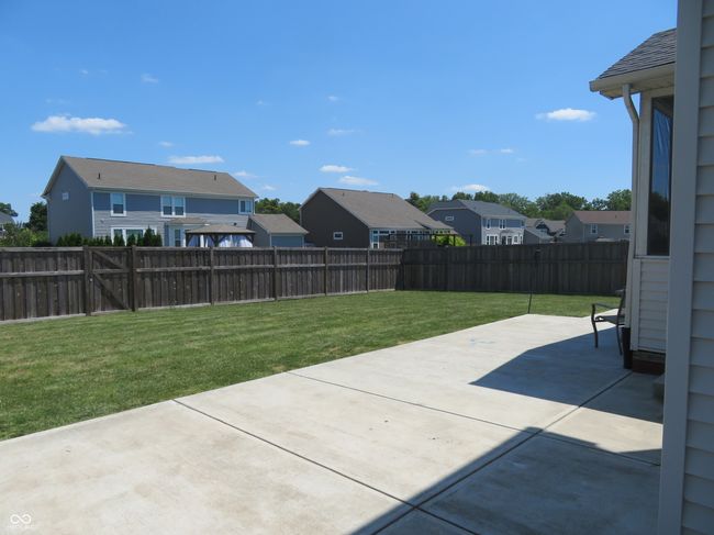 Fully fenced backyard with a large concrete patio and screened porch. | Image 5