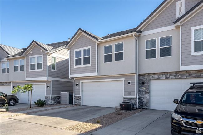 Townhome / multi-family property with stone siding, concrete driveway, and an attached garage | Image 29