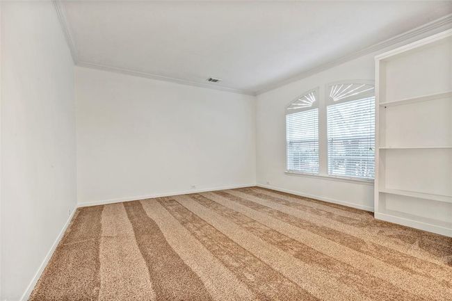 This room features neutral-toned carpet, white walls, and ample natural light from two large windows. Built-in shelving adds storage and display options, making it versatile for various uses. | Image 19