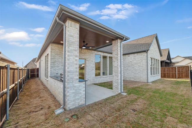 Rear view of property featuring a ceiling fan, brick siding, a fenced backyard, a patio, and a yard | Image 37