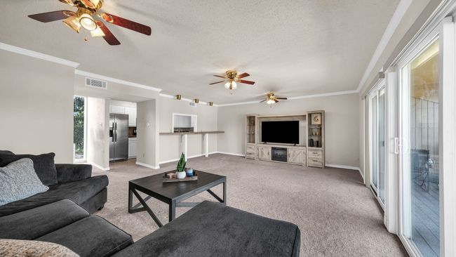 Carpeted living room featuring ceiling fan, ornamental molding | Image 8
