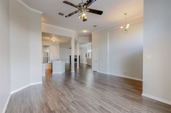Unfurnished living room featuring ceiling fan, wood finished floors, crown molding, baseboards, and a fireplace | Image 6