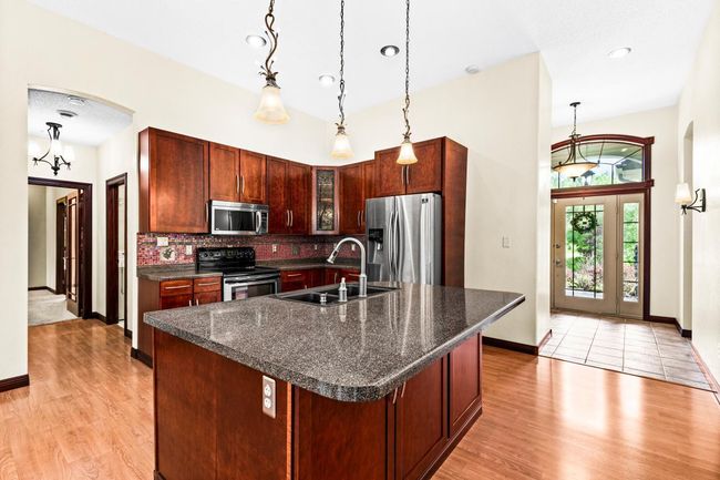 Well-appointed Kitchen features beautiful cabinetry, granite countertops, stainless steel appliances and center island with breakfast bar seating. | Image 9