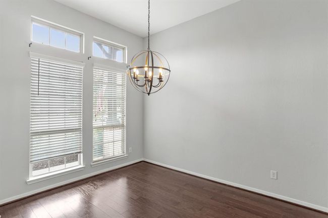 Spacious dining room in the front of the house with wood floors, pendant lighting, and large windows with privacy blinds. | Image 5