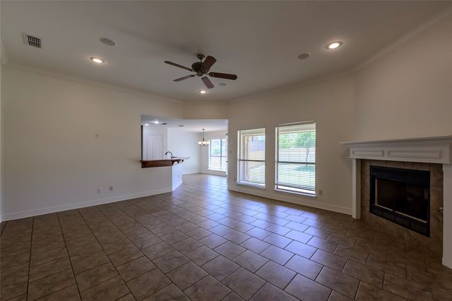 Unfurnished living room with visible vents, ornamental molding, and ceiling fan with notable chandelier | Image 15