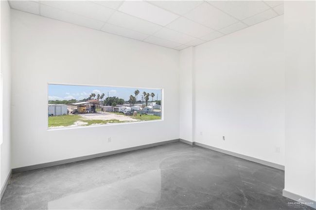 Empty room with concrete floors, baseboards, a paneled ceiling, and a towering ceiling | Image 30