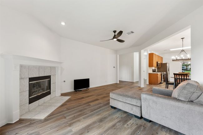 Living room featuring a ceiling fan, a tile fireplace, wood finished floors, lofted ceiling, and a chandelier | Image 18