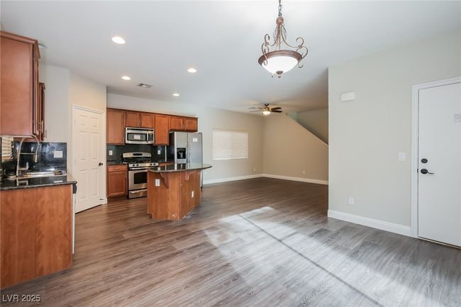 Kitchen with appliances with stainless steel finishes, dark countertops, a sink, a center island, and open floor plan | Image 5