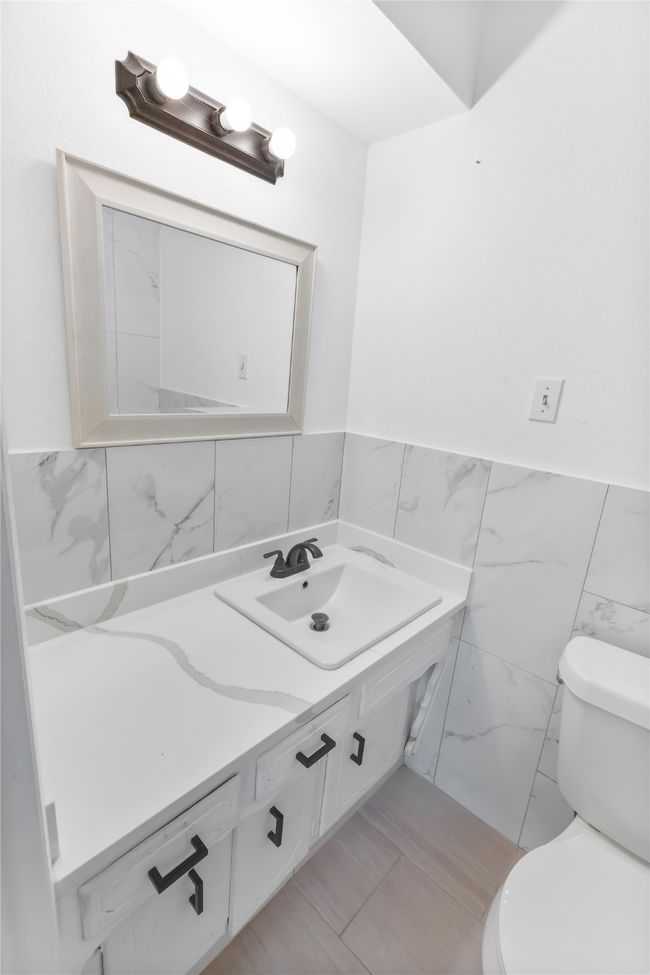 Bathroom featuring vanity, toilet, and tile walls | Image 13