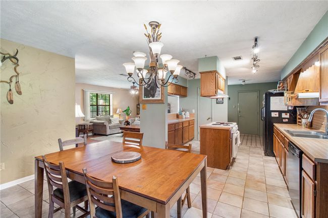 Dining space with light tile patterned floors, a chandelier, and track lighting | Image 7