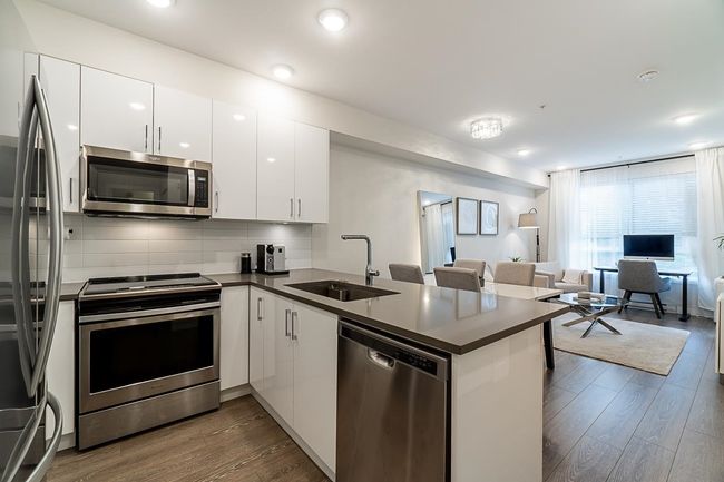 Kitchen with dark countertops, a sink, open floor plan, a peninsula, and appliances with stainless steel finishes | Image 15