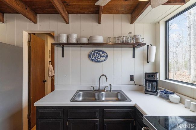 Kitchen featuring a sink, beamed ceiling, dark cabinetry, stove, and open shelves | Image 18