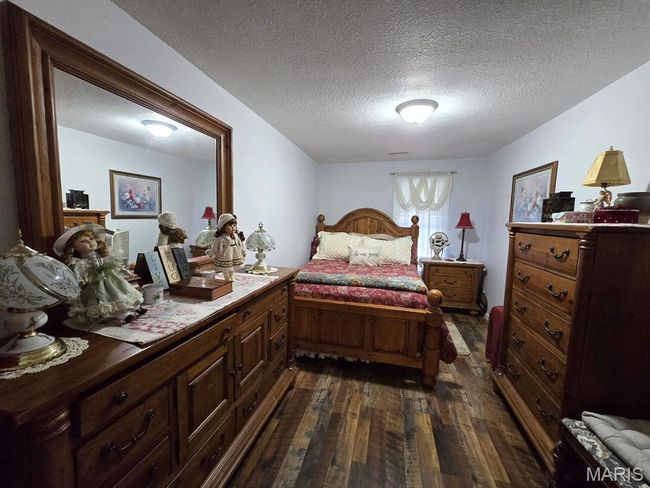 Bedroom with dark wood-style floors and a textured ceiling | Image 12