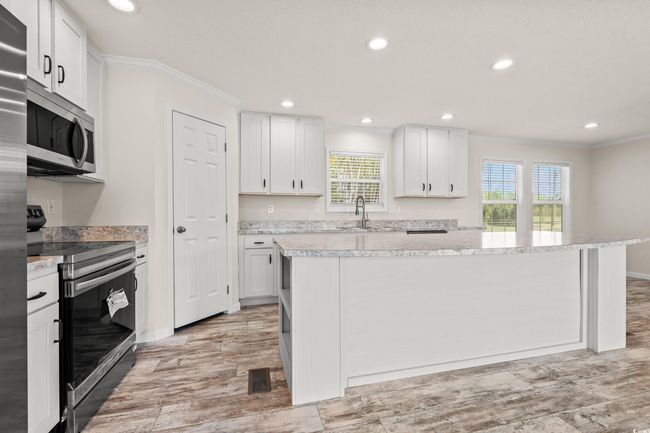 Kitchen featuring white cabinetry, a kitchen island, visible vents, stainless steel appliances, and a sink | Image 9