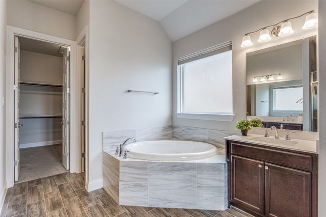 Full bathroom featuring vanity, a bath, healthy amount of natural light, wood finish floors, and vaulted ceiling | Image 10