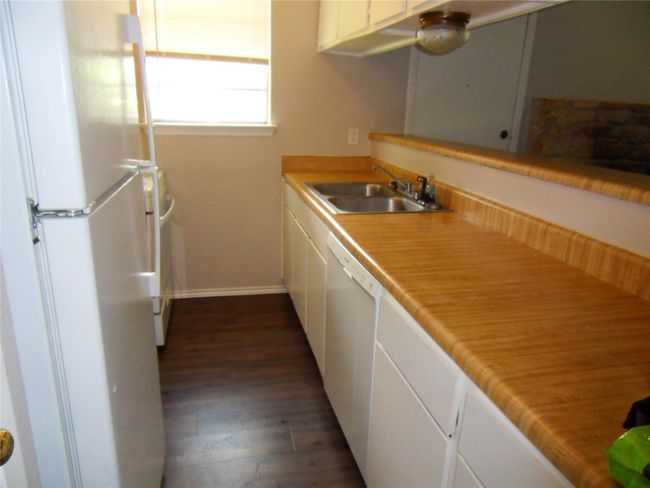Kitchen with white appliances, a sink, white cabinetry, dark wood-style floors, and baseboards | Image 6