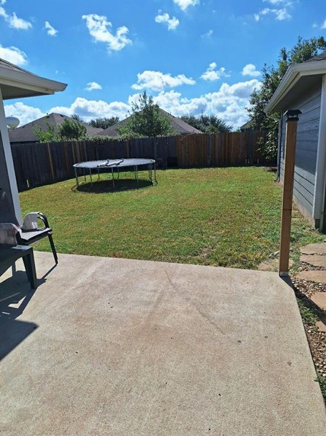 Fenced backyard featuring a trampoline and a patio | Image 7