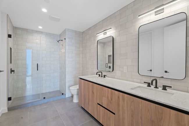 Bathroom with tile walls, a shower stall, double vanity, tile patterned flooring, and recessed lighting | Image 17