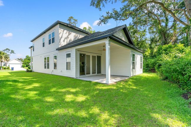 Back of property with ceiling fan, a patio area, a lawn, and roof with shingles | Image 19