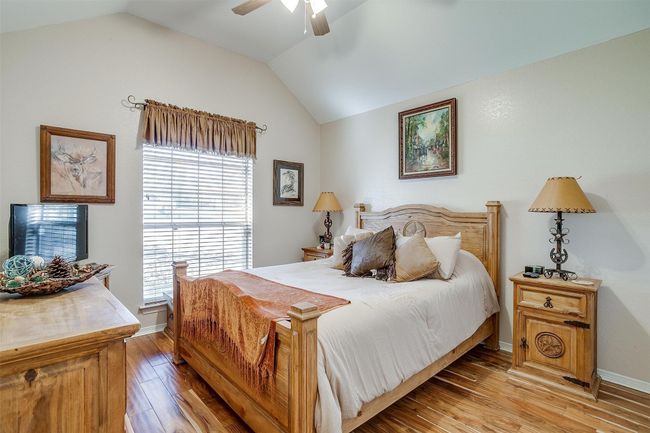 Bedroom with lofted ceiling, a ceiling fan, baseboards, and light wood-type flooring | Image 10