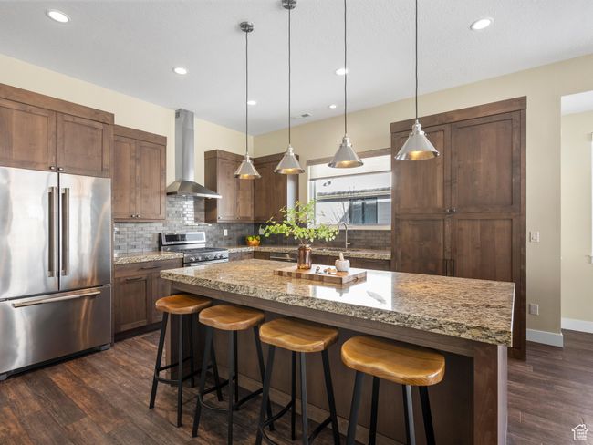 Kitchen with high quality appliances, wall chimney range hood, backsplash, a kitchen breakfast bar, and recessed lighting | Image 6