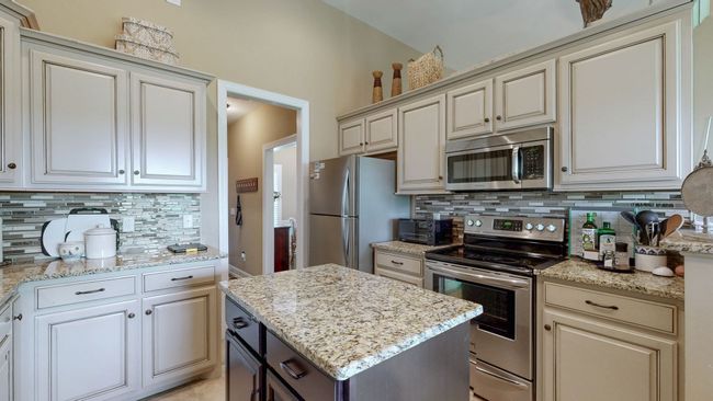 Notable touches of elegance in the kitchen are the custom cabinetry, granite countertops, tiled backsplash, and stainless steel appliances. No need to update! | Image 8
