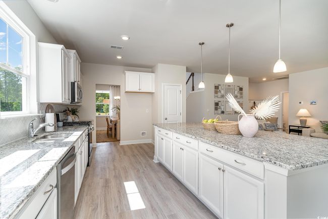 Kitchen featuring visible vents, a center island, light wood-type flooring, appliances with stainless steel finishes, and white cabinets | Image 7