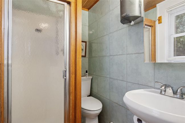 Bathroom with a shower stall, tile walls, a sink, and toilet | Image 20