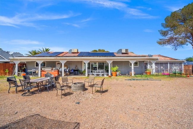 Rear view of property featuring fence, a fire pit, a patio, and roof mounted solar panels | Image 28
